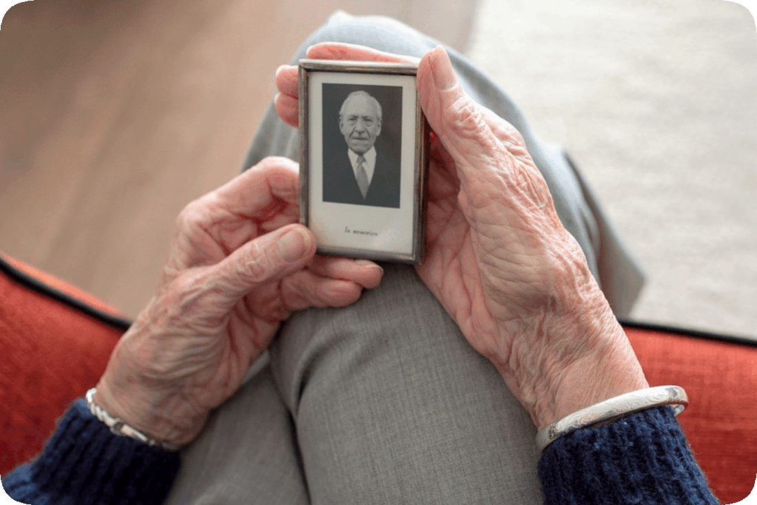 Picture of a person holding in their hands a small framed picture of a loved one.