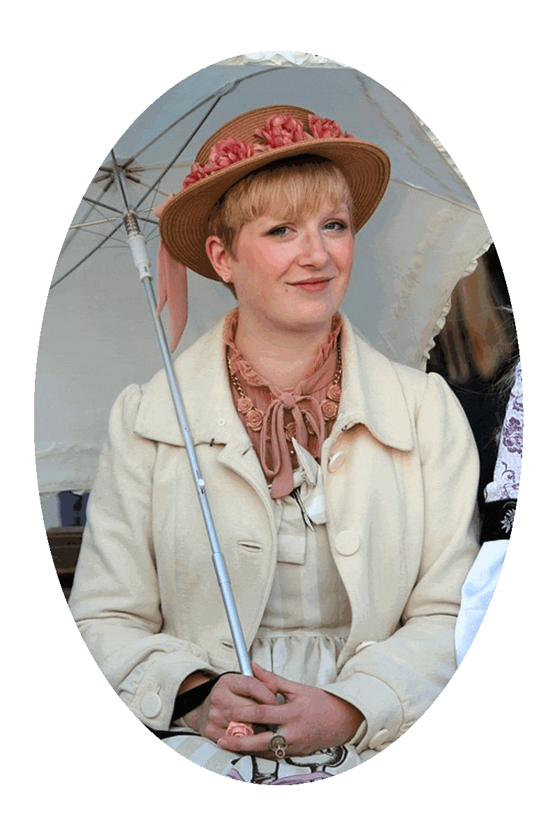 Picture of a woman seated, wearing a hat, and holding a parasol.