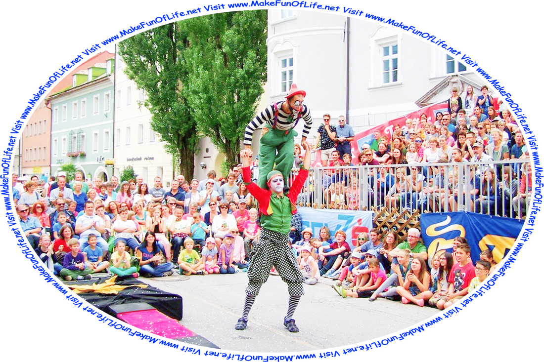 Picture of a clown standing on the shoulders of another clown as they are about to do a stunt with a springboard, while an audience watches, and the words, ‘Visit www.MakeFunOfLife.net.’