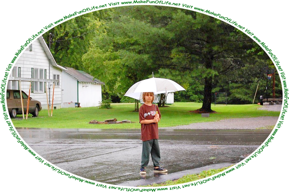 Picture of a boy holding an open umbrella above his head and standing outside of a house on a rainy day, surrounded by green grass and green leafy trees, and the words, ‘Visit www.MakeFunOfLife.net.’