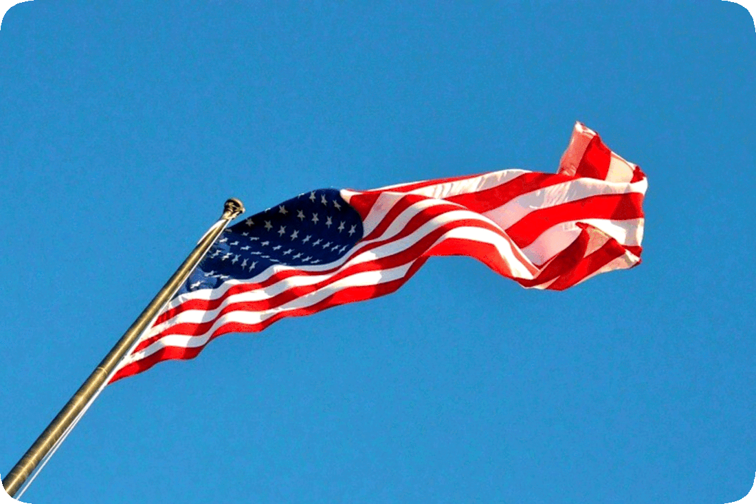 Picture of an American Flag waving in the breeze against a clear blue sky.