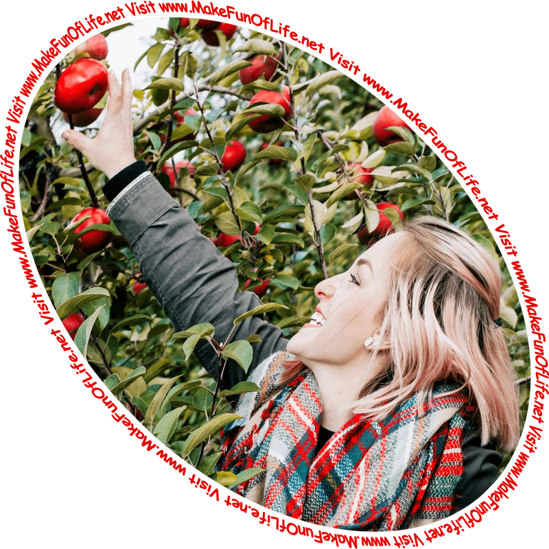 Picture of a happy smiling woman reaching upward to pick a red apple from an apple tree branch and the words, 'Visit www.MakeFunOfLife.net.'