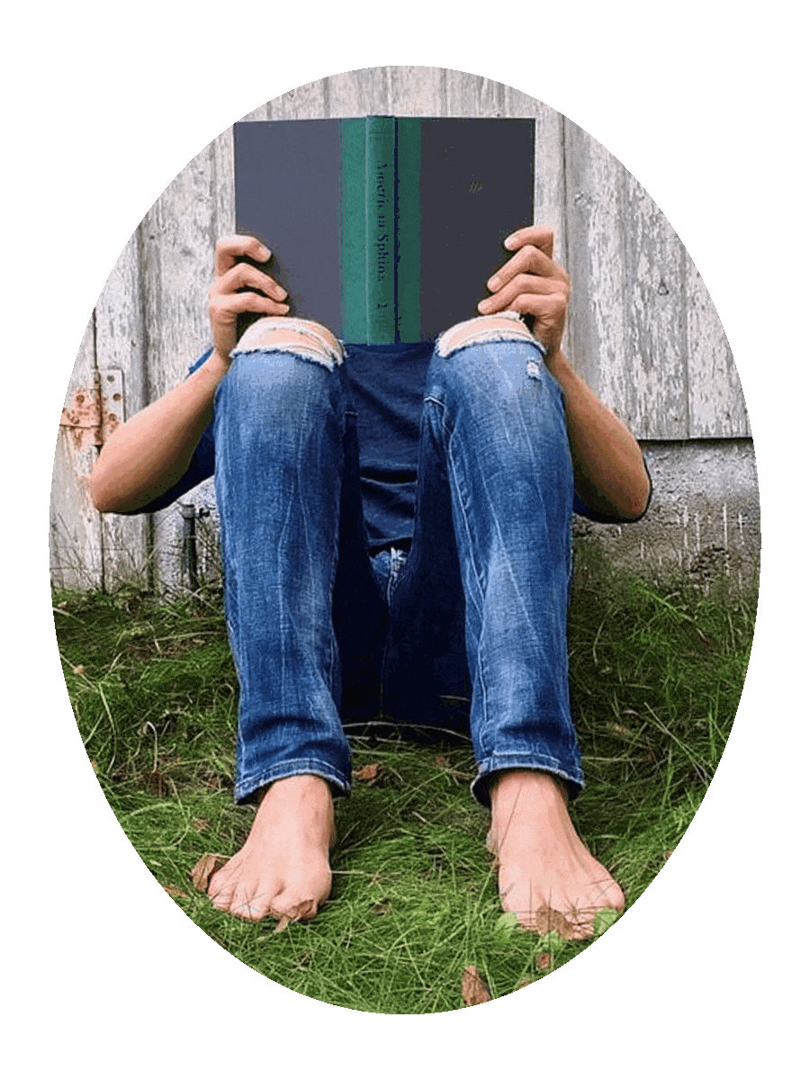 Picture of a barefoot person sitting in green grass and reading a book.
