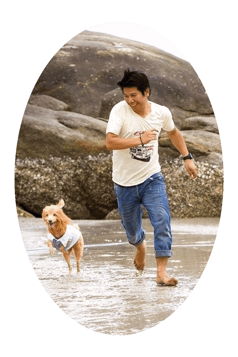 Picture of a barefoot man running alongside a dog on a wet sandy beach.