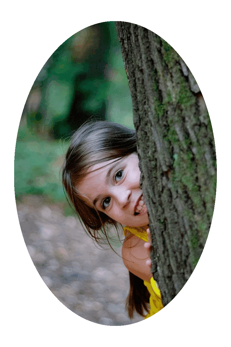 Picture of a girl looking out from behind a tree trunk.