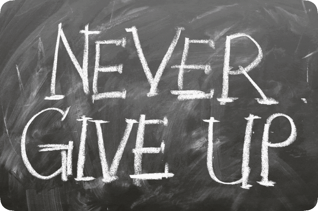 Picture of a chalk board with chalk writing reading, ‘Never Give Up.’
