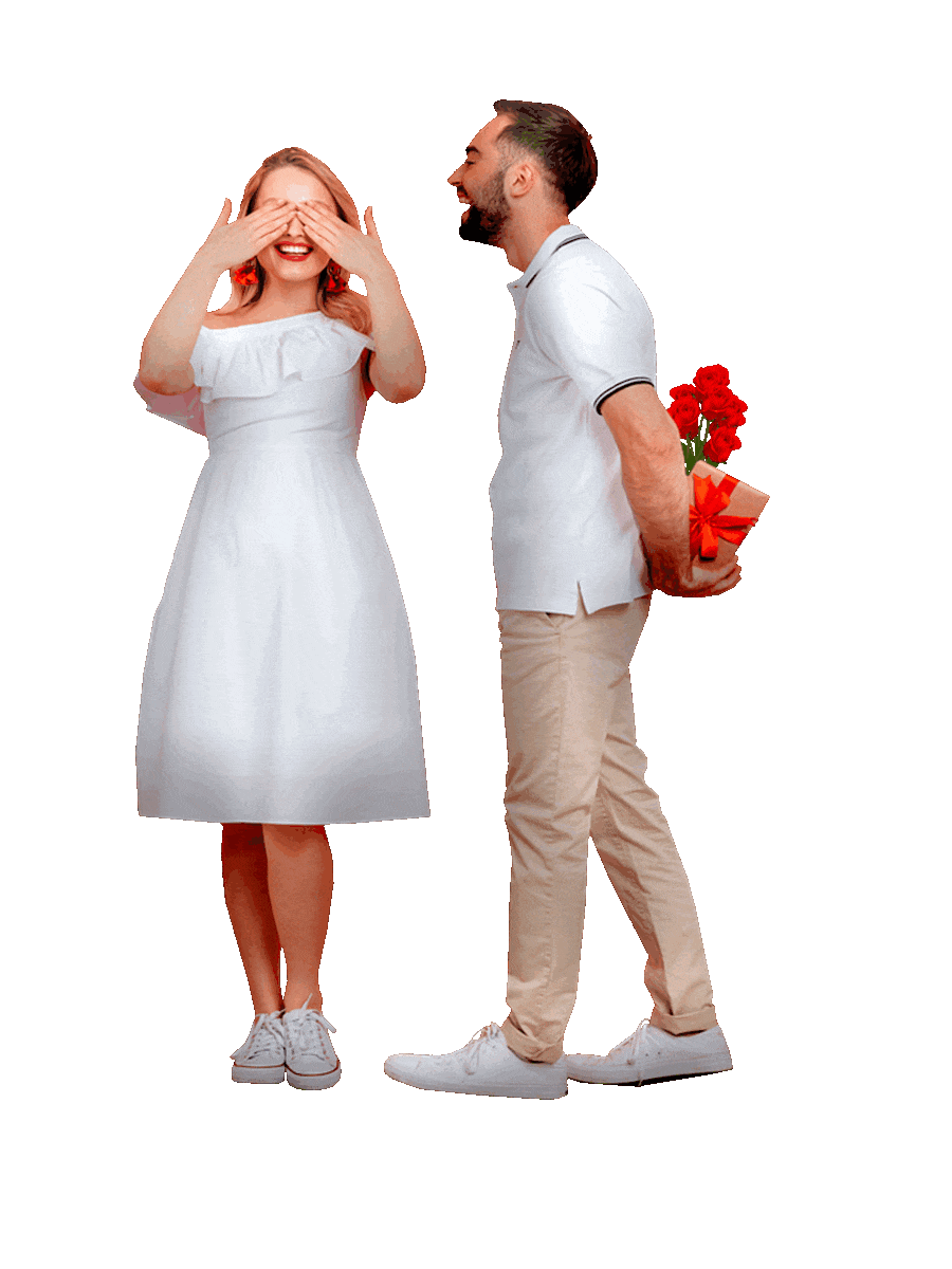 Picture of a smiling happy woman covering her eyes with her hands in anticipation of a surprise and standing next to a smiling happy man who is holding in his hands a gift box wrapped in a red ribbon and bow and a bouquet of red roses hidden behind his back.