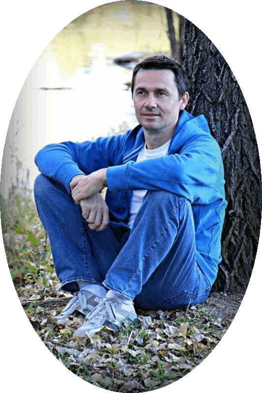 Picture of a man sitting on the ground with his back against a tree trunk.