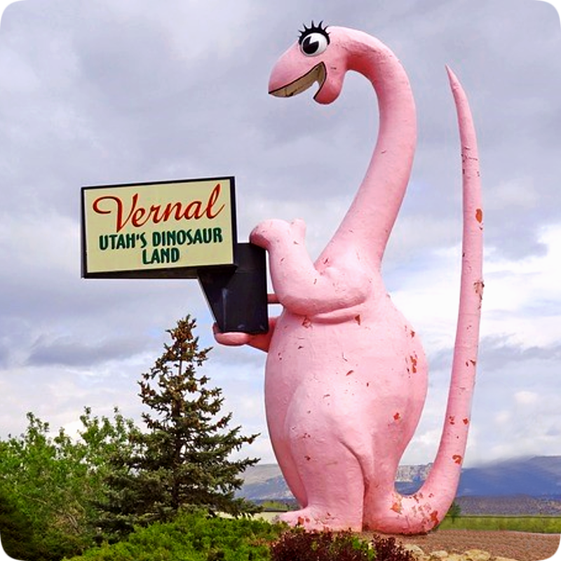 Picture of a tall pink dinosaur holding a sign reading, 'Vernal - Utah's Dinosaur Land.'