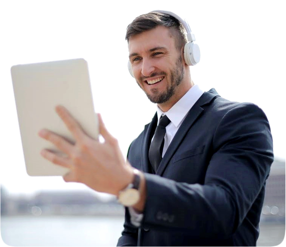 Picture of a happy smiling man dressed in a suit and necktie while holding a computer tablet and wearing headphones