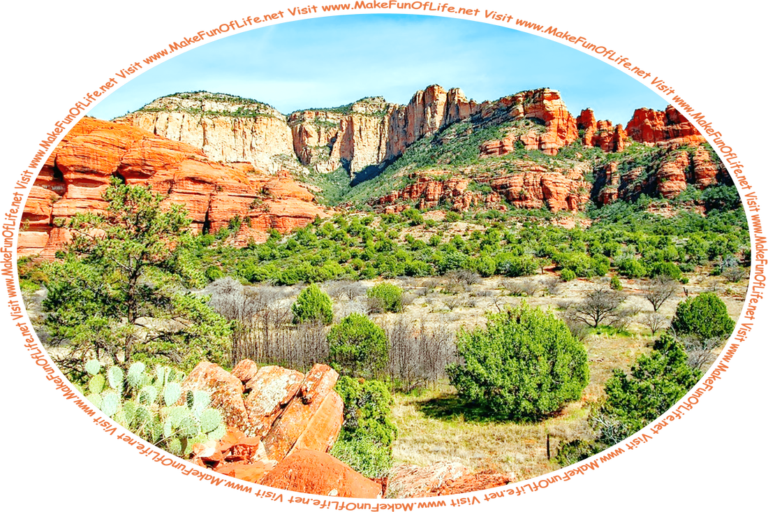Picture of a desert with exposed red and tan rock outcroppings, during the growing season, with green leafy shrubs and cactuses, a hazy blue sky above, and the words, ‘Visit www.MakeFunOfLife.net.’