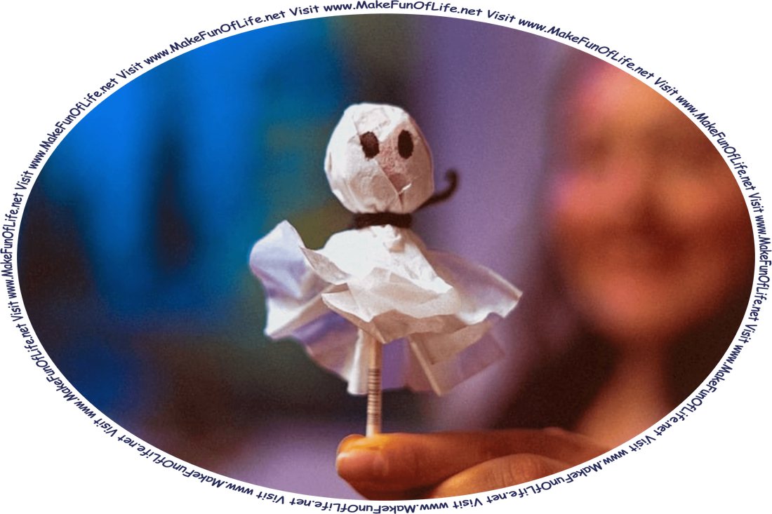 Picture of a lollipop ghost party favor, made by placing a piece of paper over a lollipop and tying it together where the stick meets the candy, and drawing two eyes on it, and the words, ‘Visit www.MakeFunOfLife.net.’