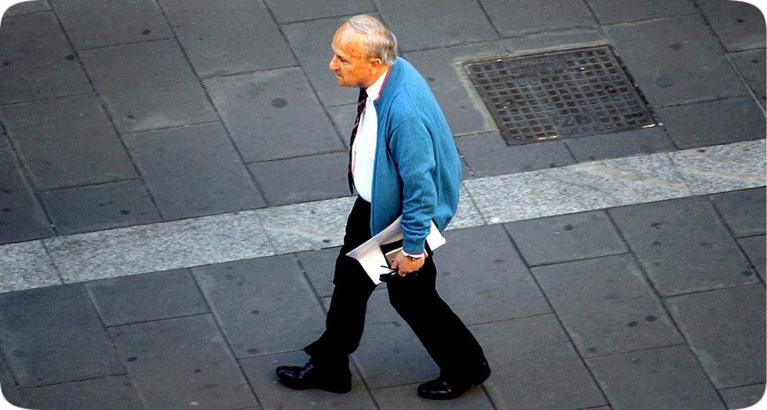 Picture of a man walking with head lowered and projected forward well past the chest, shoulders slumped, and stomach out, a posture that might be improved through learning and practicing good posture while walking, also known as gait