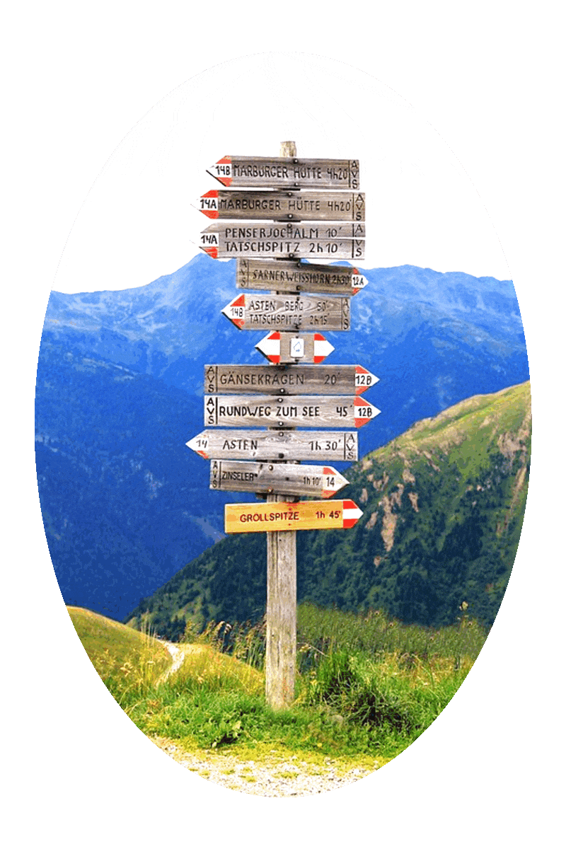 Picture of a sign post in a mountainous area, with the names of cities and distances to the cities on arrow-shaped signs, with the mountains and hills and an overcast sky above.