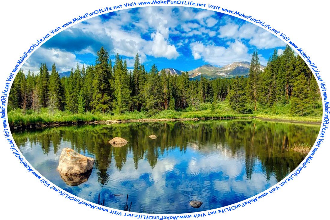 Picture of a of a clear blue mountain lake surrounded by green grass and evergreen trees, with a blue sky and white fluffy clouds above, and the words, ‘Visit www.MakeFunOfLife.net.’
