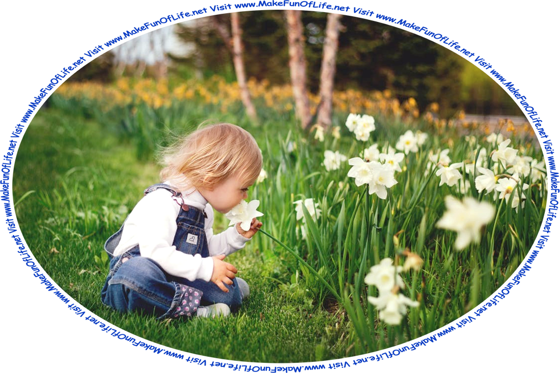 Picture of a young child sitting cross-legged in green grass and bending forward to grasp and smell a white flower.