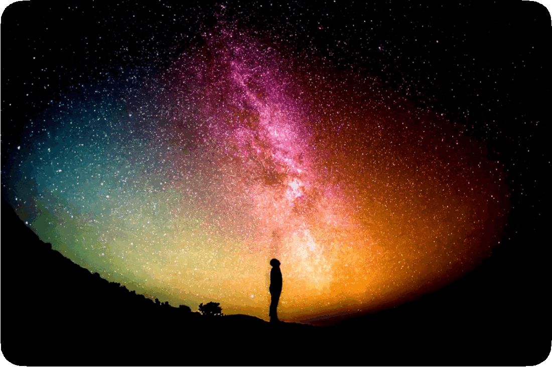 Nighttime picture of a person in silhouette standing and gazing upward at the stars.