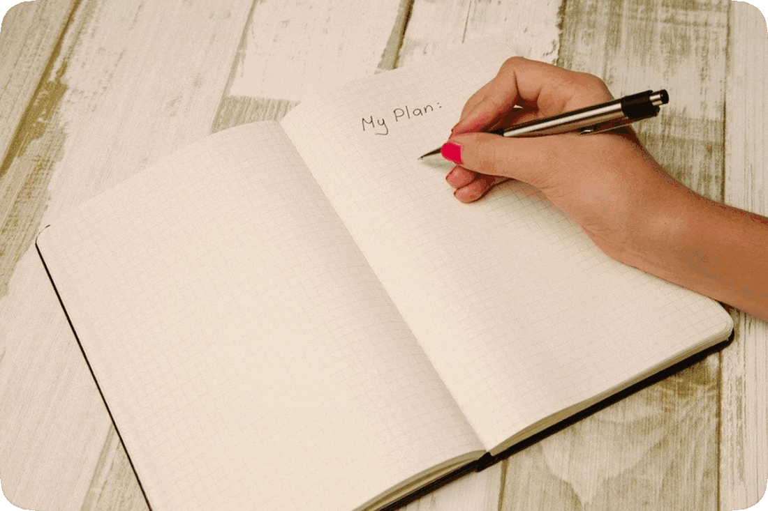 Picture of an open notebook with the words, ‘My Plan,’ written at the top of one page, and a person’s hand holding a pen.