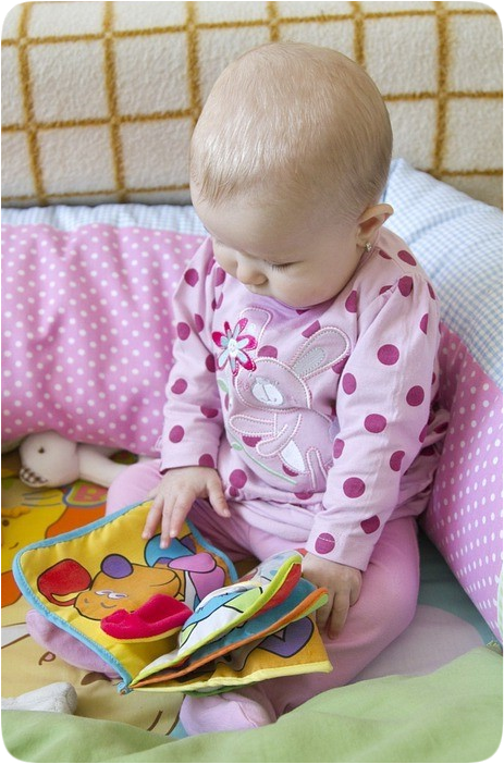 Picture of a baby looking at a picture book.